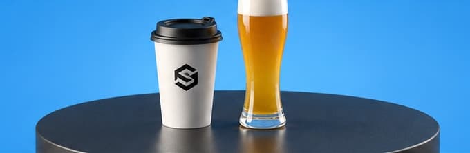 Kaffeebecher und Weissbierglas auf einem runden Tisch